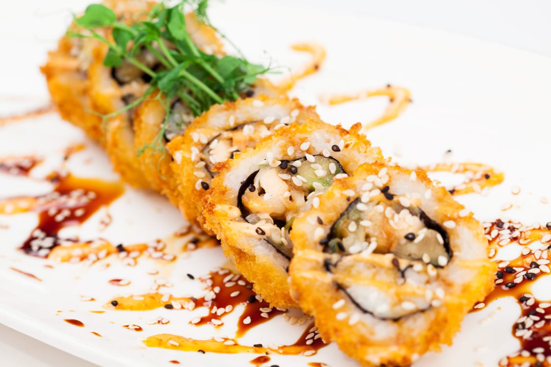 Breaded sushi roll on plate with sauce