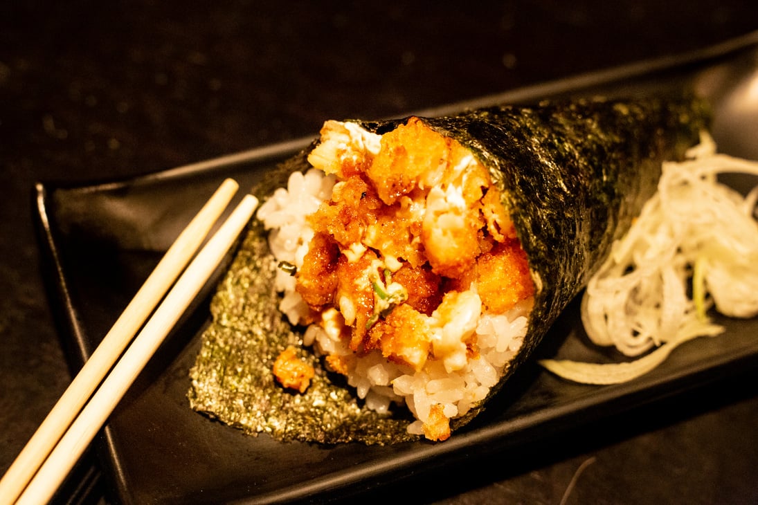 Shrimp temaki sushi on black plate on wood background.